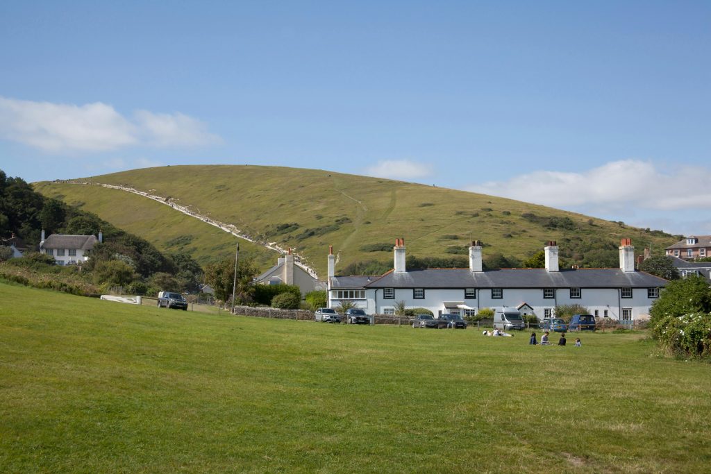 Charming countryside scene with cottages and rolling hills in Lulworth Cove, Dorset.